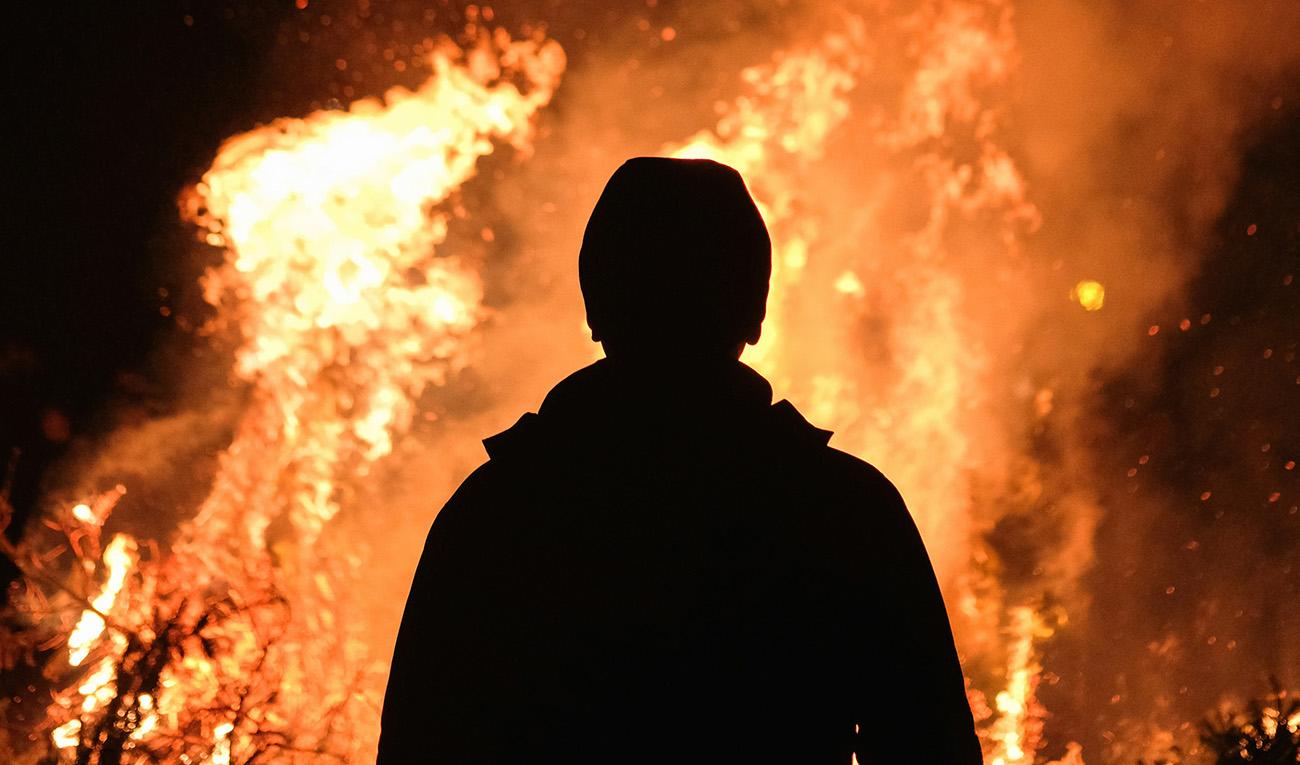 Silhouette of a person in front of a bonfire burning bright
