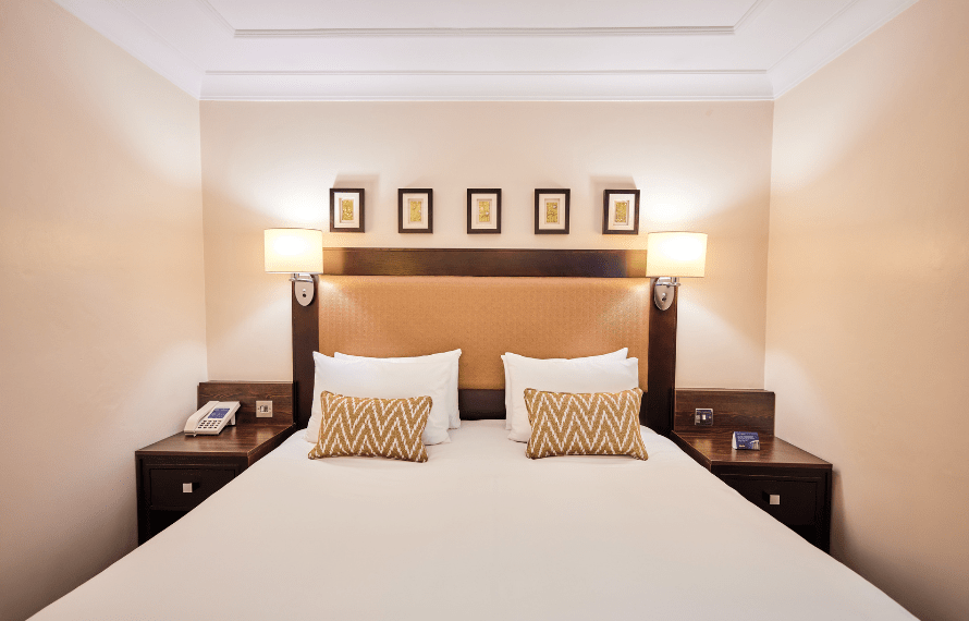 Deluxe King bedroom with large bed, bedside lamps, and framed artwork above the headboard.