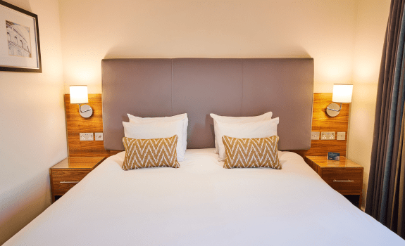 Deluxe King bedroom with large bed, bedside lamps, and headboard