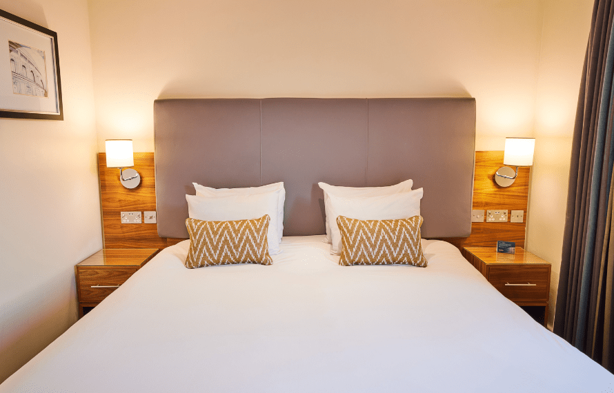 Deluxe King bedroom with large bed, bedside lamps, and headboard