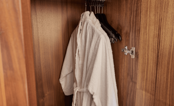 Wooden wardrobe with bathrobe and hangers inside.