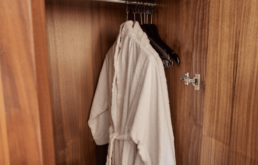 Wooden wardrobe with bathrobe and hangers inside.