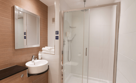 Modern bathroom with walk-in shower, sink, and mirror.