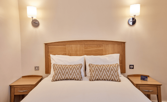 Standard Double bedroom with wooden headboard, bedside tables, and soft lighting.