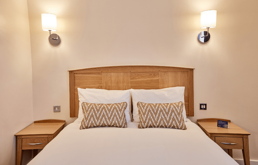Standard Double bedroom with wooden headboard, bedside tables, and soft lighting.