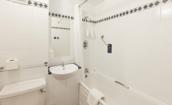 Bathroom with bathtub, shower, and white tiled walls.