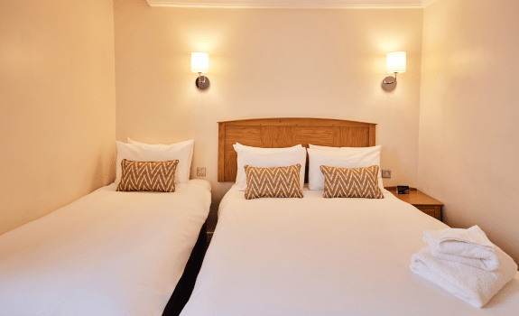 Family bedroom with double and single beds, wooden headboard, and bedside tables.