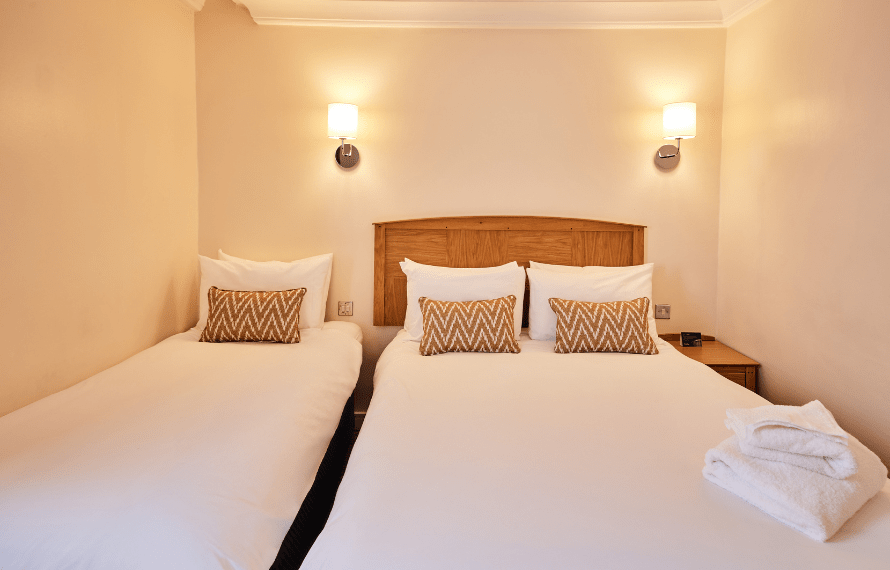 Family bedroom with double and single beds, wooden headboard, and bedside tables.