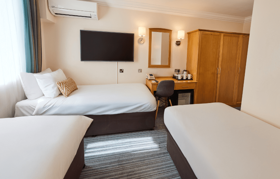 Standard Family bedroom with three single beds, desk area, wardrobe, and wall-mounted TV.