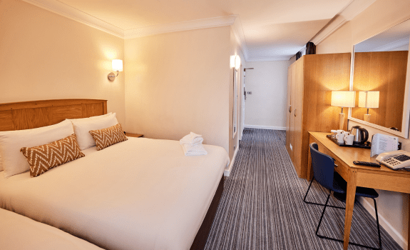 Family bedroom with double and single beds, desk area with kettle and wardrobe.