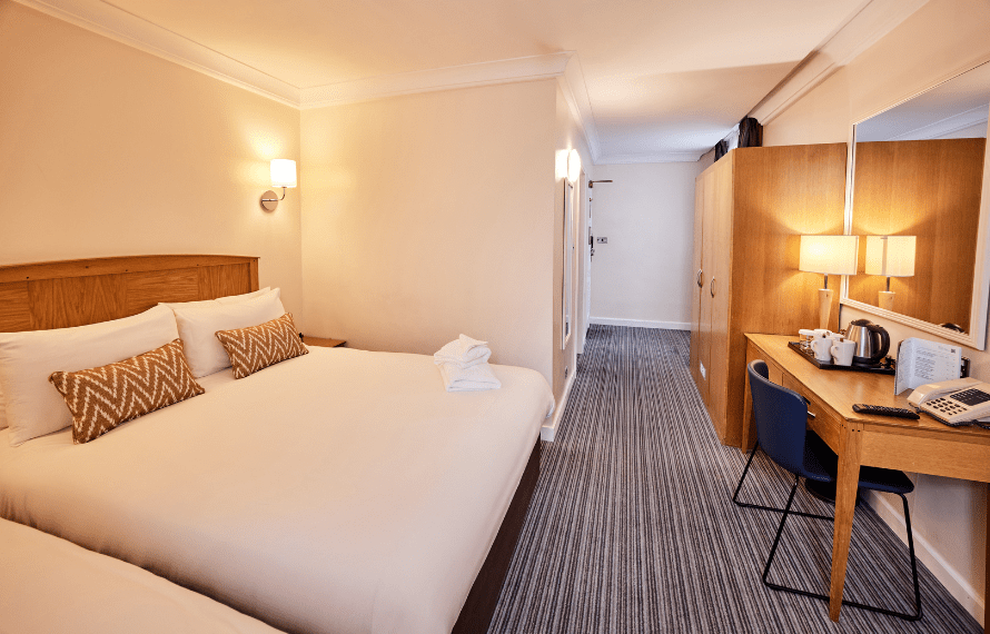 Family bedroom with double and single beds, desk area with kettle and wardrobe.