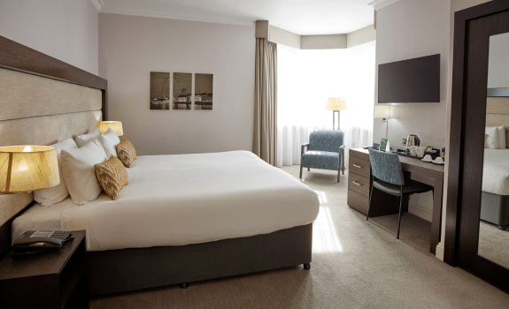 King bed in executive room with TV, desk and bedside tables