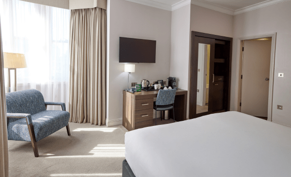 Desk, TV, armchair and bed in executive room
