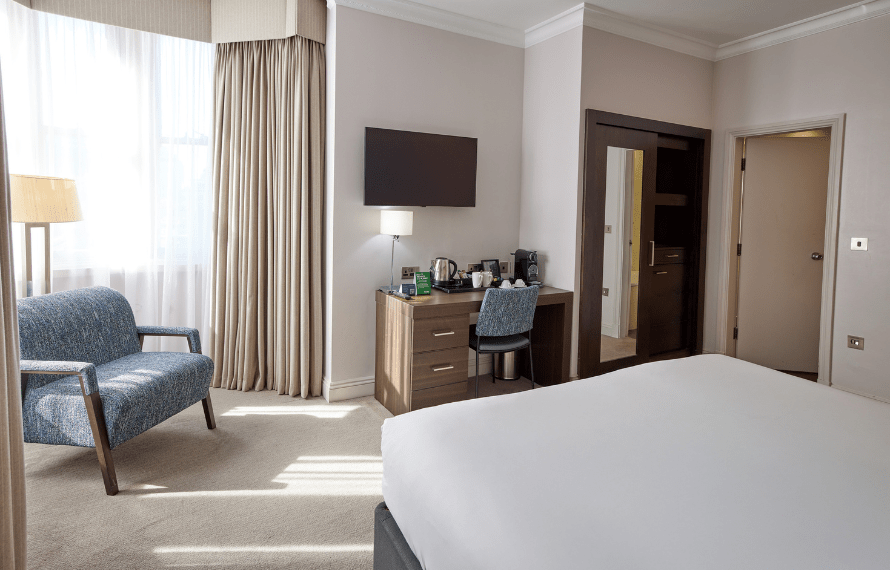 Desk, TV, armchair and bed in executive room