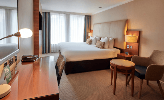 View of deluxe king room with king bed and desk