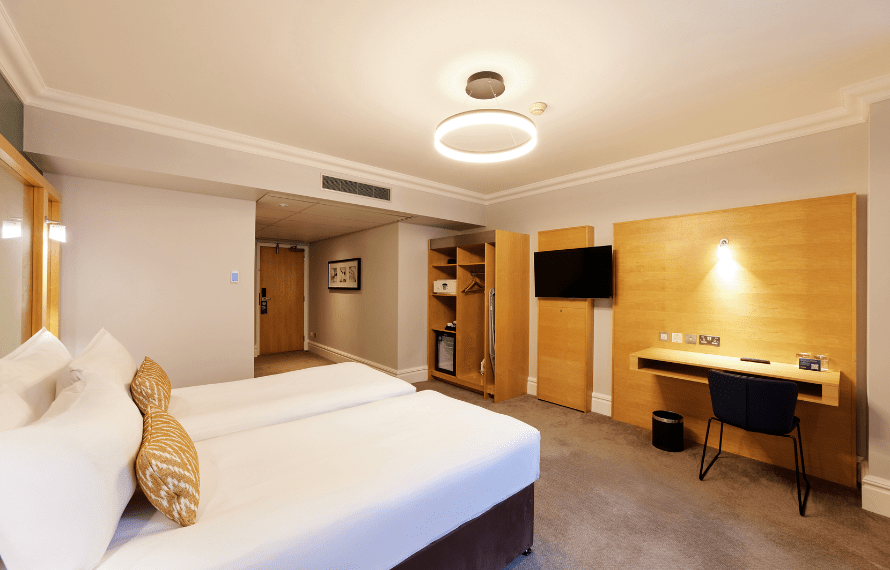 Twin beds and desk with TV on the wall