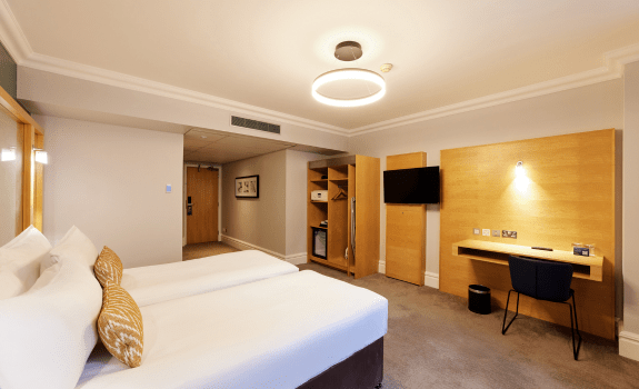 Twin beds and desk with TV on the wall