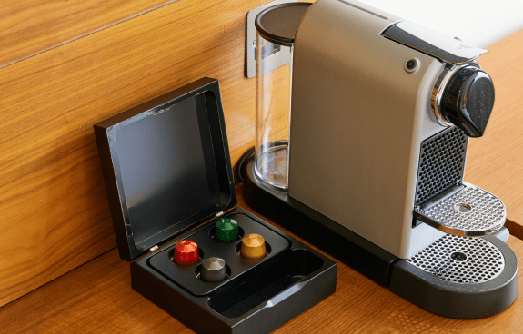 In‑room Nespresso coffee machine with capsule selection placed on a wooden counter.