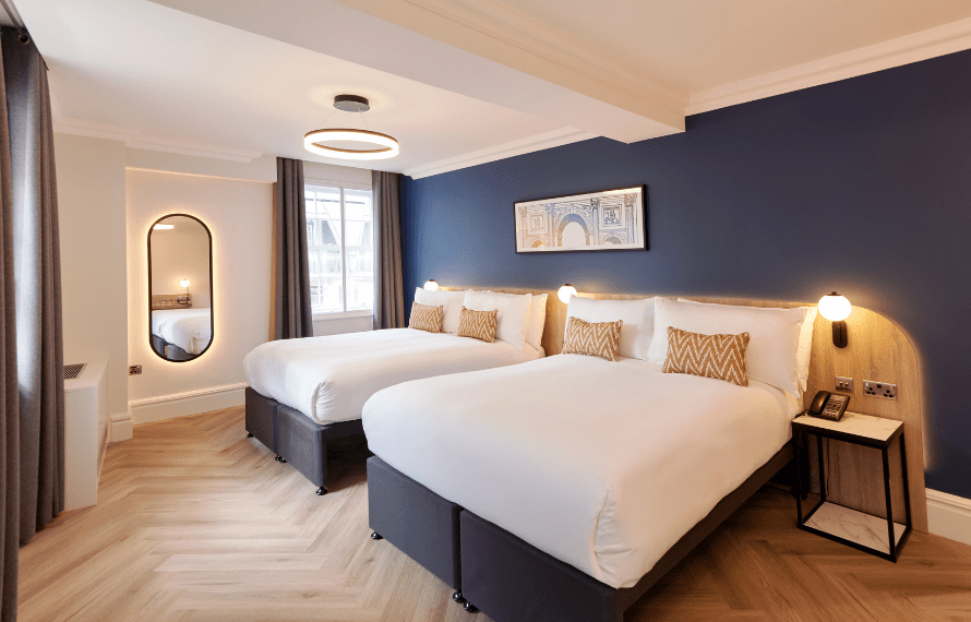 Deluxe family room at Thistle Park Lane with two beds, patterned cushions, wall lighting and mirror.