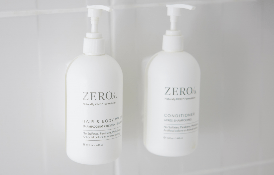 Wall‑mounted Zero% branded hair and body wash and conditioner bottles in a hotel shower.