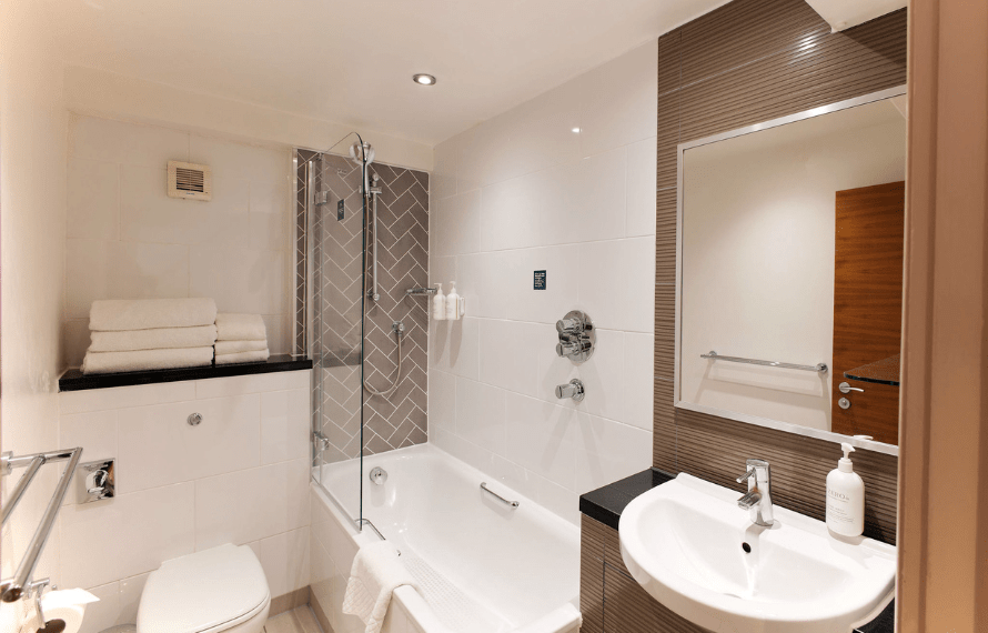 Deluxe king bathroom with a bathtub, shower, sink, toilet, and herringbone-patterned tiles