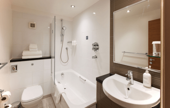 Bathroom with a bathtub, shower, sink, toilet, and herringbone-patterned tiles